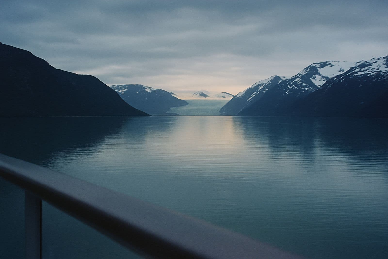 A still fjord and distant glacier seen from a balcony rail