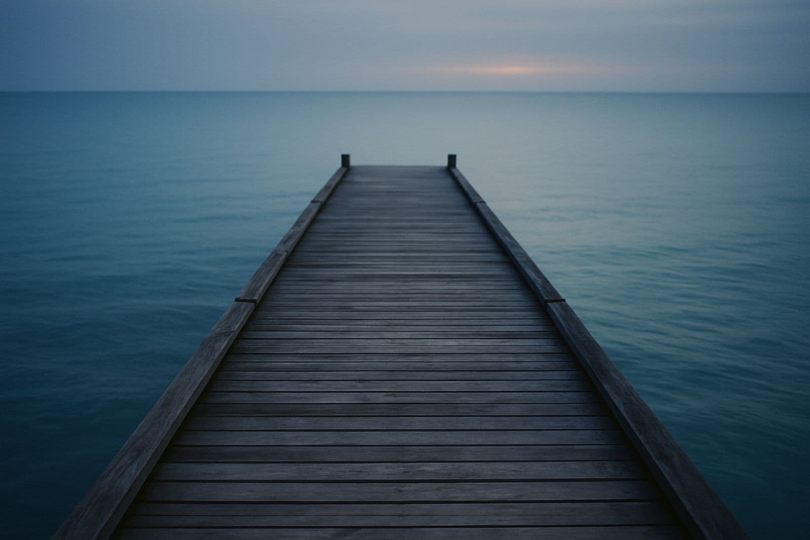 An empty wooden pier running out over calm water