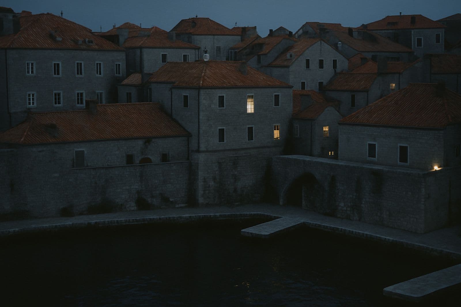 Terracotta rooftops above a small stone harbour at dusk