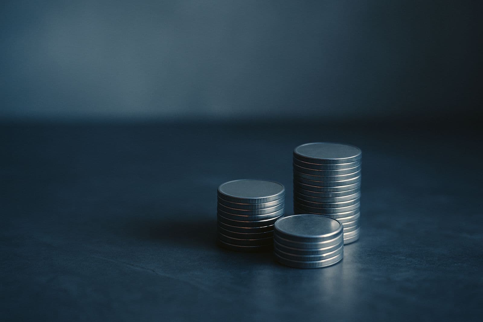 Three short stacks of coins on a slate surface