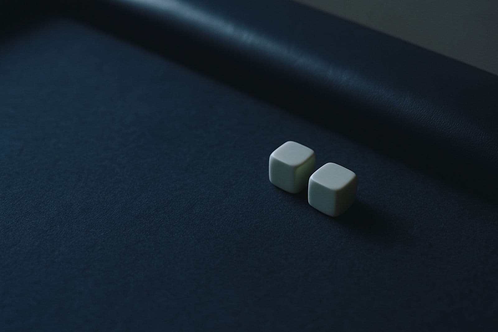 A pair of dice on blue felt beside the table rail