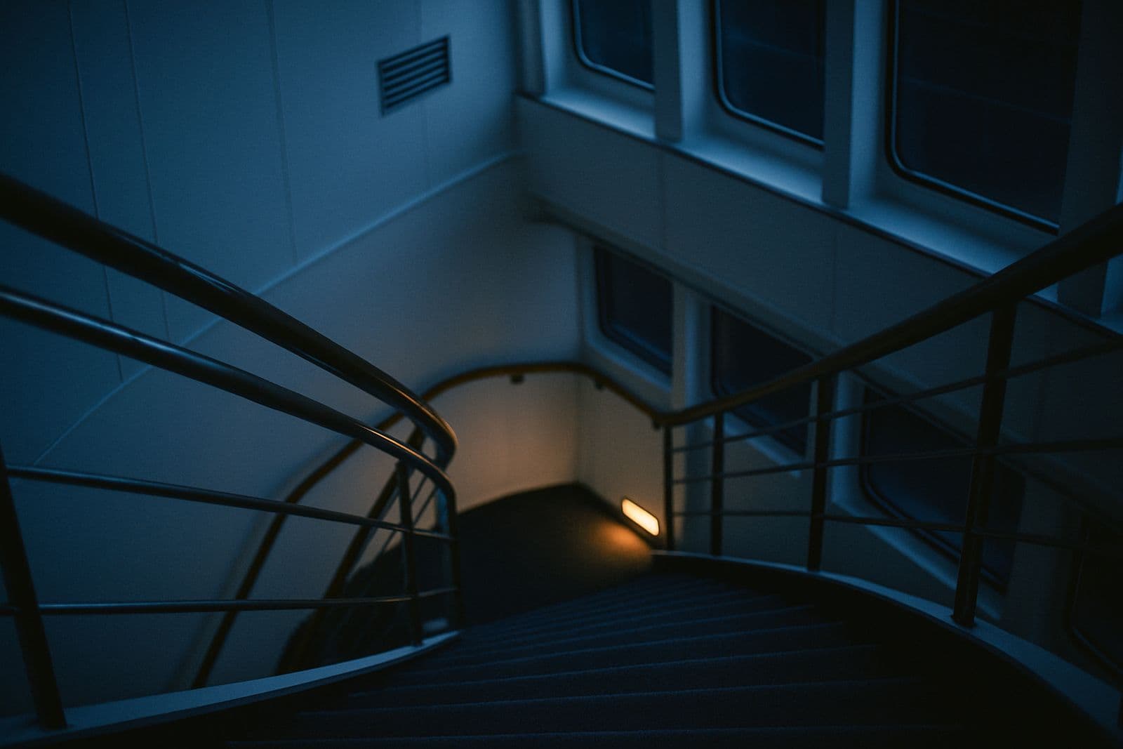 A curving staircase and handrail inside a quiet ship atrium