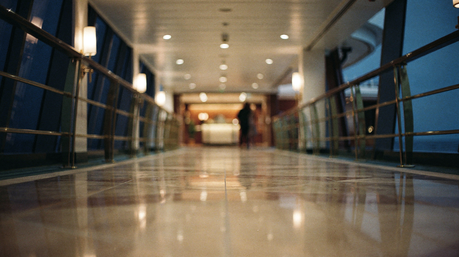 Cruise ship casino floor at night, rows of glowing slot machines reflected in dark floors, open ocean visible through cu